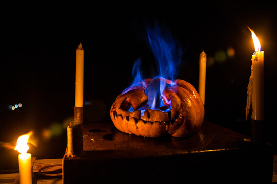 Horror Halloween concept. Close up view of scary dead Halloween pumpkin glowing at dark background. Rotten pumpkin head.