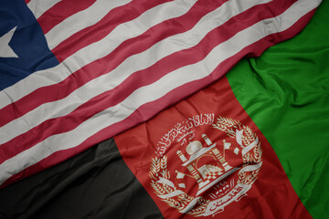 waving colorful flag of afghanistan and national flag of liberia. macro