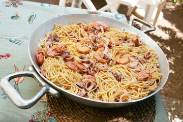 Spaghetti with clams, shrimps, baby octopus, on a pan. Pasta.