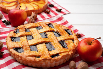 Autumn thankgiving pies on white wooden board decorated with dry leaves and cinnamon sticks