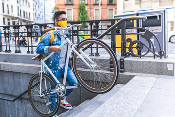 Fototapeta premium Latino Young Man Carrying Bike Going Upstairs From Underground . Transport Concept.