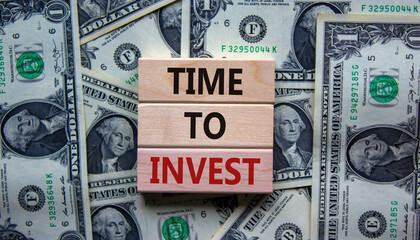 Concept text 'time to invest' on wooden blocks on a beautiful background from dollar bills....