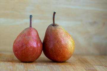Two pears edible fruits, tasty ripened red yellow fruit on wooden background