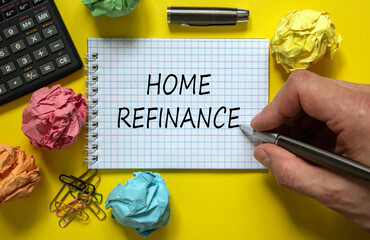 Mail hand writing 'home refinance' on white note, beautiful yellow background, colored paper clips, metalic pen, cap and calculator. Business concept.