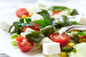Healthy Salad with Feta Cheese, Green Olives, Baby Spinach, Cucumber, Cherry Tomatoes and Capers. Bright background. Close up.