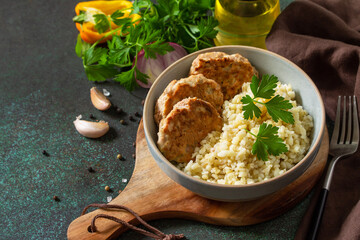 Healthy vegan food. Red fish cutlets with bulgur on a dark stone or slate table.