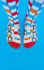 aerial view of the feet in sandals and colored socks on a blue background