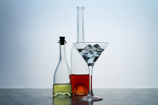 Two clear crystal bottles and a glass,  with red and yellow liquid, located at the empty background. Beautiful cocktail set with ice at the bar.