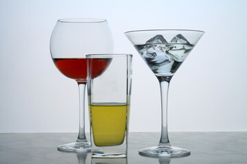 Three clear crystal glasses of different shape located at the empty background. Beautiful cocktail set with ice at the bar.