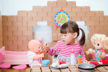young  girl pretend play babysitting with baby doll at home