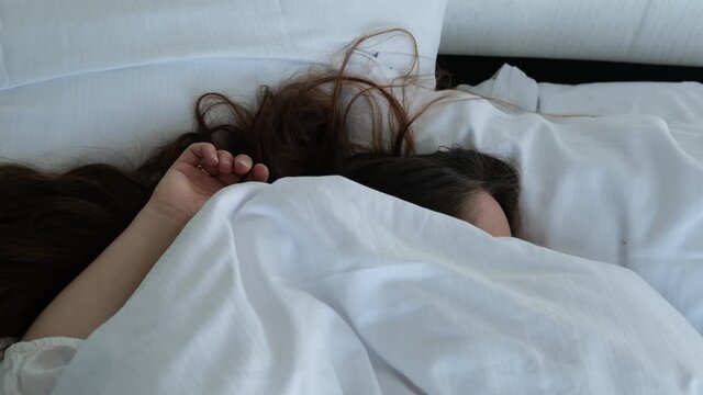 young woman with long hair is fast asleep in bed at home or hotel, concept of healthy sleep, insomnia, vacation, good mood, female happiness