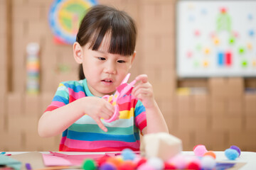 young girl using scissors cutting papper for making craft for homeschooling