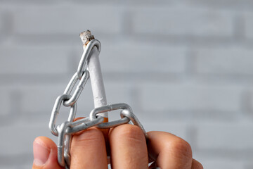 Male hand in metal chains holding cigarette