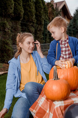 A boy and his mother cut a pumpkin. A young mother and son are preparing a pumpkin for Halloween. Preparing for Halloween. Peel an orange pumpkin.