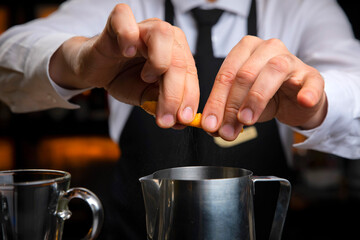 Fototapeta na wymiar bartender in a black apron holds an orange peel 