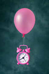 Alarm clock flying up on a balloon on a dark background.Time flies concept