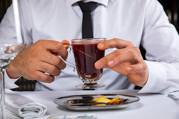 A man holds a hot alcoholic beverage in a restaurant
