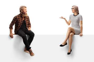Bearded guy sitting on a white panel and listening to a young woman talking