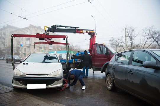 Traffic police officers on the street lifting the car on the tow truck