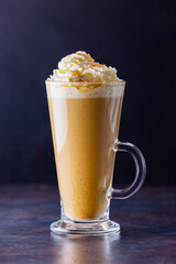 Pumpkin latte on a dark background. Pumpkin spice latte with whipped cream. Autumn drink. Minimalism. Copy space