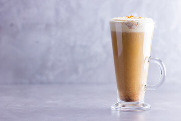 Pumpkin spice latte on a gray background. Pumpkin latte with whipped cream. Hot autumn drink. Minimalism. Copy space