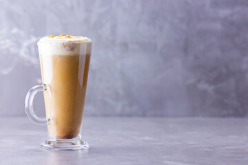 Pumpkin spice latte on a gray background. Pumpkin latte with whipped cream. Hot autumn drink. Minimalism. Copy space