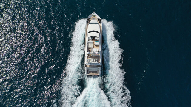 Aerial drone photo of small luxury yacht with wooden deck cruising open ocean deep blue sea