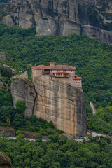 Fototapeta na wymiar Vertical photo of Rousanou Monastery. Beautiful scenic panoramic view, ancient traditional greek building on the top of huge stone pillar in Meteora,Thessaly, Greece, Europe on a cloudy day.