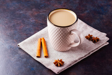 Masala chai tea. Traditional indian drink - masala tea with spices on black background. Ceramic cup...