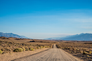 Fototapeta na wymiar dirt road in desert valley heading toward distant mountains in California 