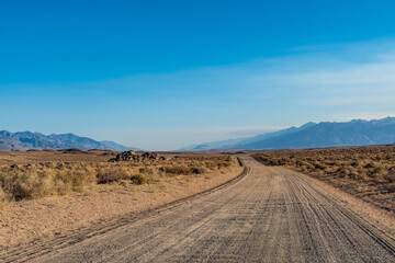 Fototapeta na wymiar dirt road in desert valley heading toward distant mountains in California 