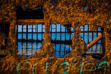 Interior of Dimitrios shipwreck in  Gythio, Greece. A partially sunk rusty metal shipwreck decaying through time on a sandy beach on a sunny day. Famous shipwreck in greece.