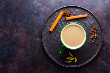 Masala chai tea. Traditional indian drink - masala tea with various spices on a black plate. Ceramic cup of spices tea on a dark background. Minimalism