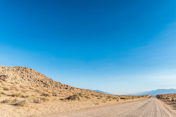 dirt road in desert valley heading toward distant mountains in California 