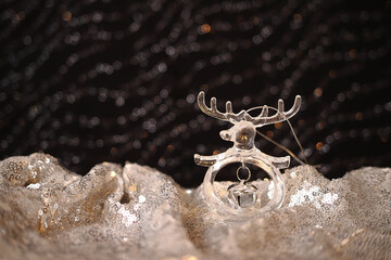 glass Christmas tree toy in the form of a deer with a bell on a shiny silver background. Christmas decorations
