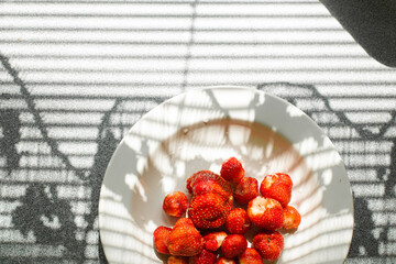 Top view of a ceramic plate full of fresh and sweet organic strawberries picked in the garden in...