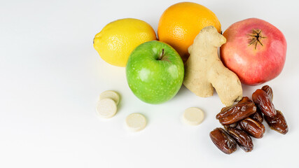 Heap of fruits ( green apple, limon, orange, garnet), ginger, dates and multivitamins for immunity stimulation and viruses defence. Healthy food for boost immune system.