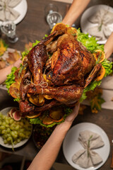 Top view of hands of female passing roasted turkey to her husband or father