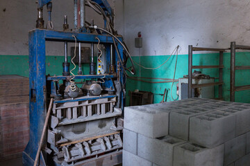 Industrial production of building cement pressed materials. High quality hollow concrete block or cement brick and hydraulic press. Finished products stacked on pallets dry after the press.