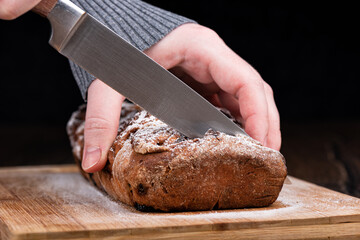 Soft focus. The girl is holding a homemade raisin pie and is trying to cut it with a knife.