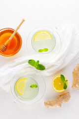Ginger tea with lemon and mint on a white napkin. Two cups of ginger tea, lemon, ginger root and honey on white background. Top view