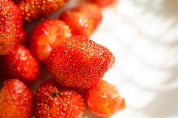 Macro stock photo of large organic sweet strawberries in sunlight. Strawberry texture in close-up. Seeds and dirt.
