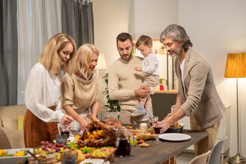 Two blond females and mature grey-haired man bending over served table