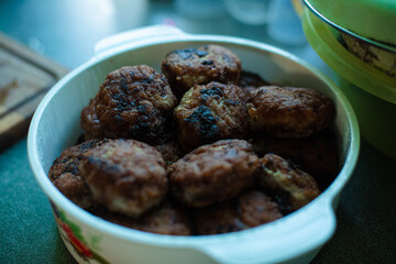 Plenty of ready-made fried meatballs lie in a large white aluminum pan on the table.