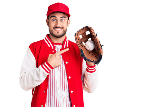 Young handsome man holding baseball gloves smiling happy pointing with hand and finger