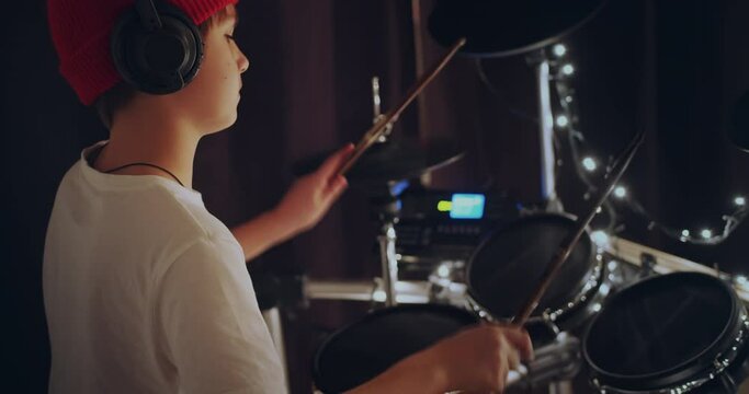 Cool and talented young boy playing drums in white tshirt performing song in dark background feeling super star on stage. Teenager rock band drummer