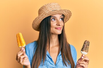 Young hispanic woman wearing summer style holding ice cream smiling looking to the side and staring...
