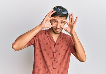 Young handsome man wearing casual summer clothes trying to open eyes with fingers, sleepy and tired...