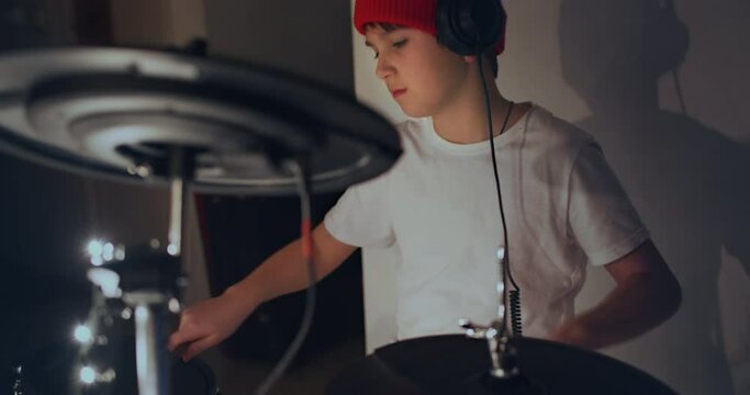 Happy young boy practice playing electronic instrument drums at musical studio. Teenager rock band drummer. Self learning and remote education