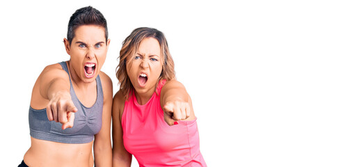 Fototapeta na wymiar Couple of women wearing sportswear pointing displeased and frustrated to the camera, angry and furious with you